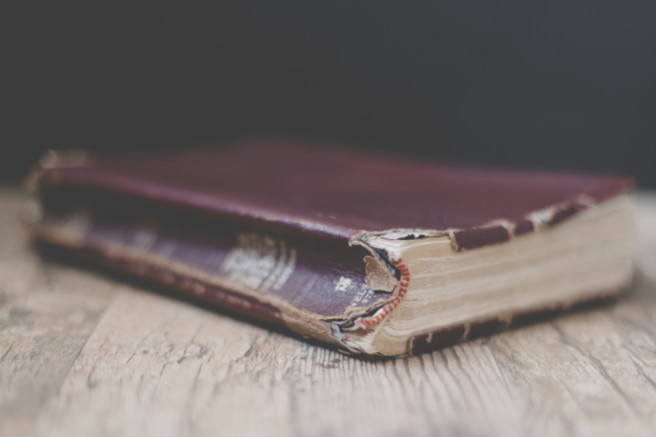 A worn red-leather Bible resting on a wooden table